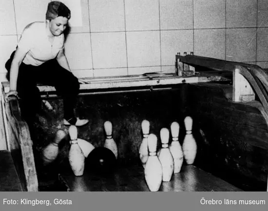 En kvinna som sätter upp käglorna vid bowlingbana.