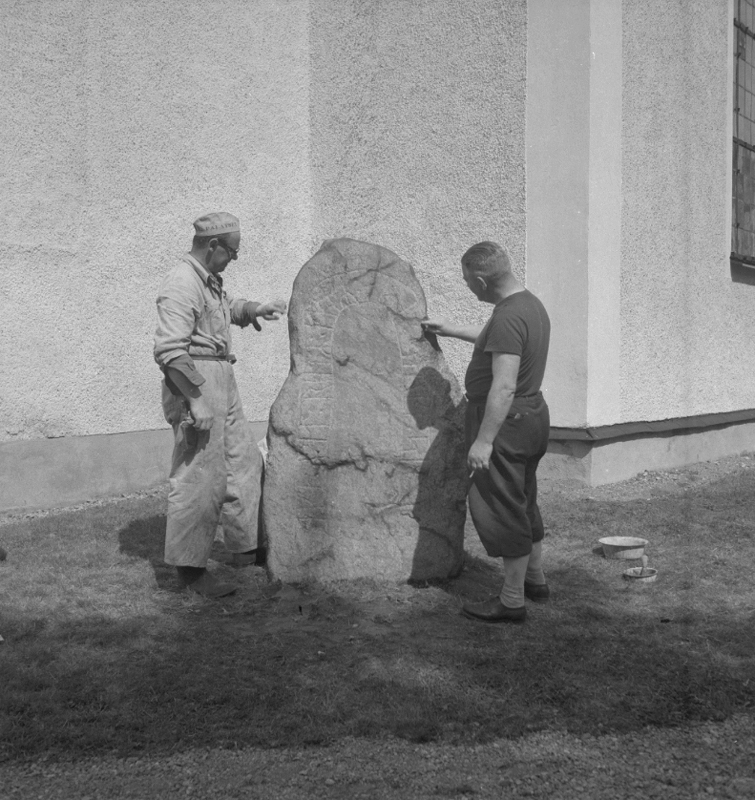 Stora Mellösa kyrka, exteriör. Runsten vid kyrkan, två personer.
14 juni 1952.