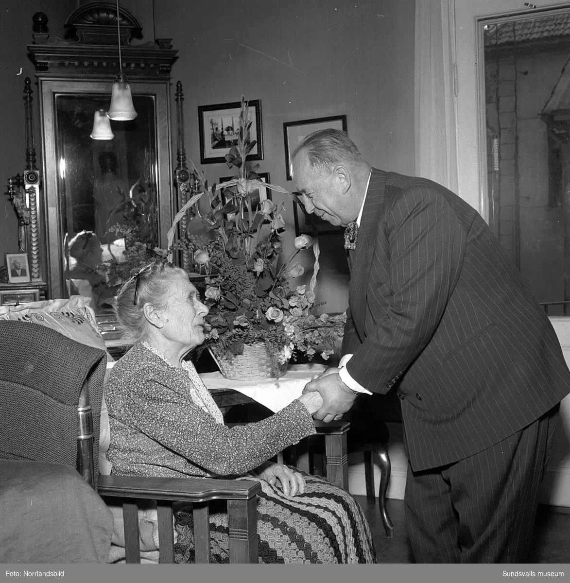 Lindgrens järnhandel firar 100-årsjubileum. Direktör Fridolf Brunnzell uppvaktar fru Palmqvist med en minnesskrift, samt kaffekalas på ett ålderdomshem.