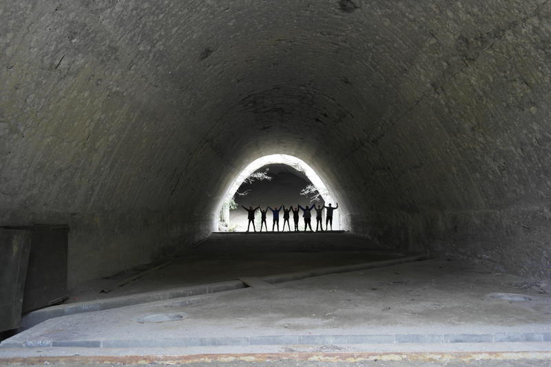 8 elever står i enden av et tunnel. De holder hverandre i hånden