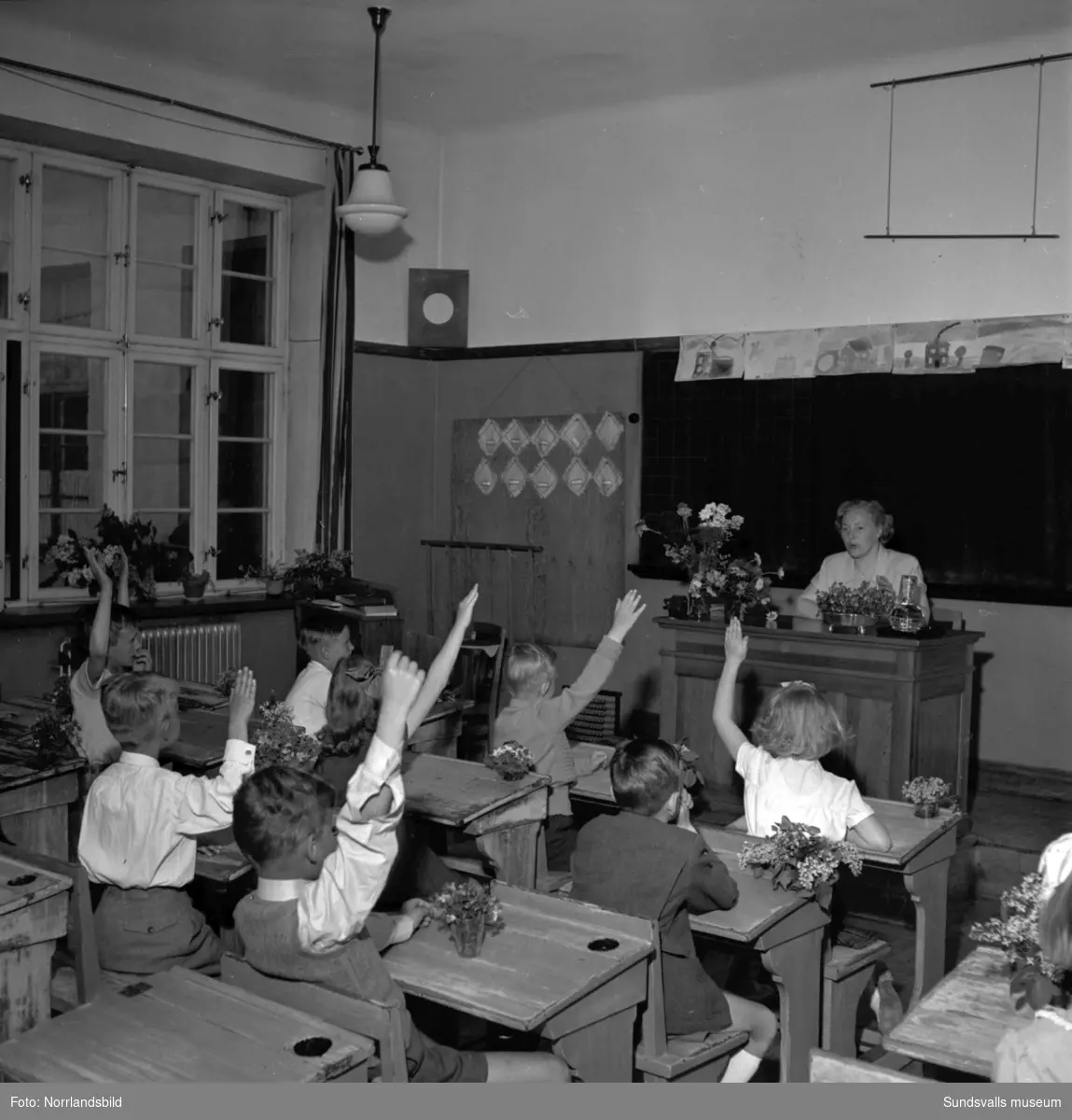 Skolavslutning på Höglundaskolan med barn, föräldrar, syskon och fröken i klassrummet.
