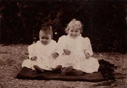 To små barn Erica? og Tinken) sitter på et teppe.