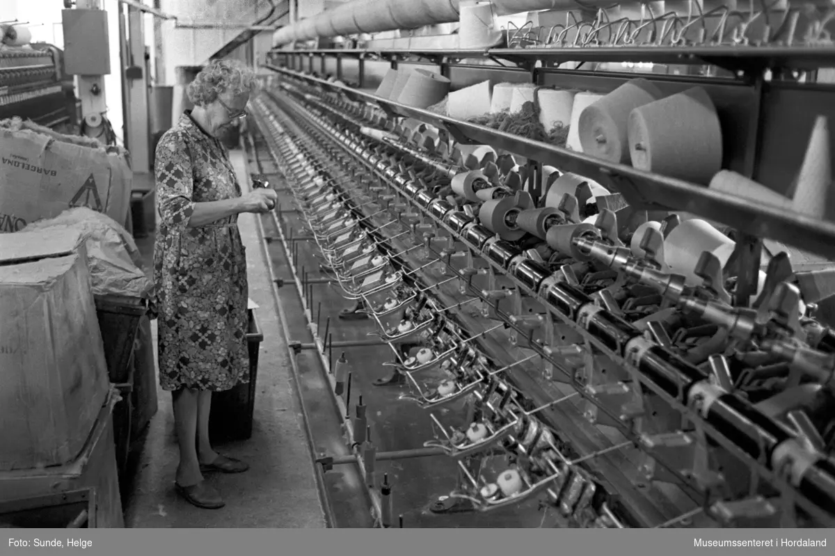Arbeidsliv ved Salhus Tricotagefabrik i Salhus, Bergen i 1976. Kvinne arbeidar ved spolemaskin i 1910-bygget på Salhus Tricotagefabrik.
