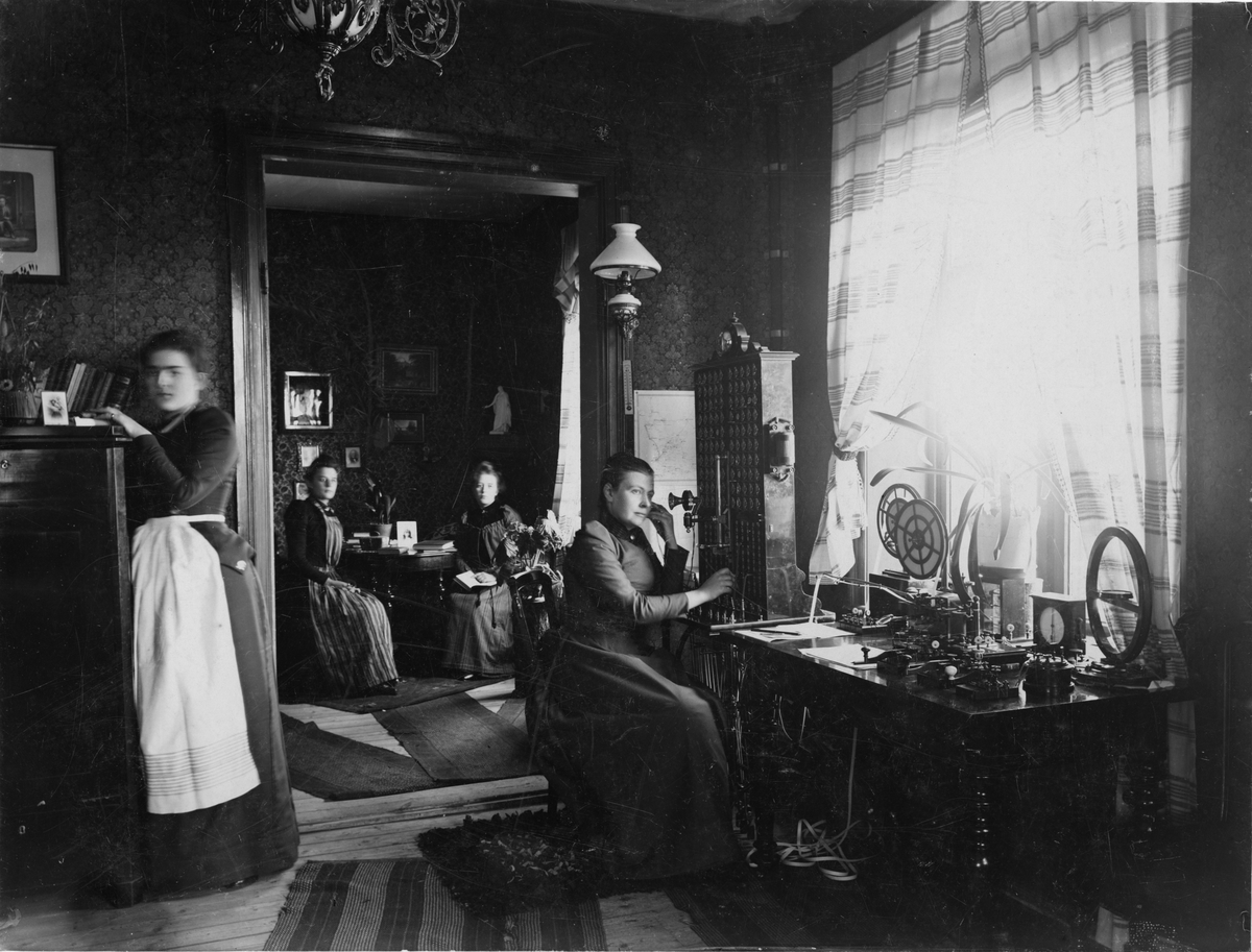 Telegraf- och telefonstation (troligen rikstelefon) med telegrafapparater och telefonväxelbord (100-linjers väljare) av L.M. Ericssons tillverkning från 1880-talet. Fotot troligen taget vid sekelskiftet 1900. Möjligen i Eslöv.