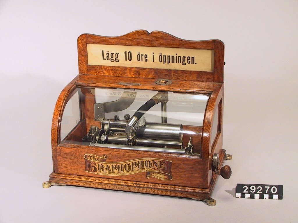 Fjäderdriven fonograf med fast vev, med automatisk spelning för en kostnad av 10 öre. Skyltens höjd: 115 mm.
