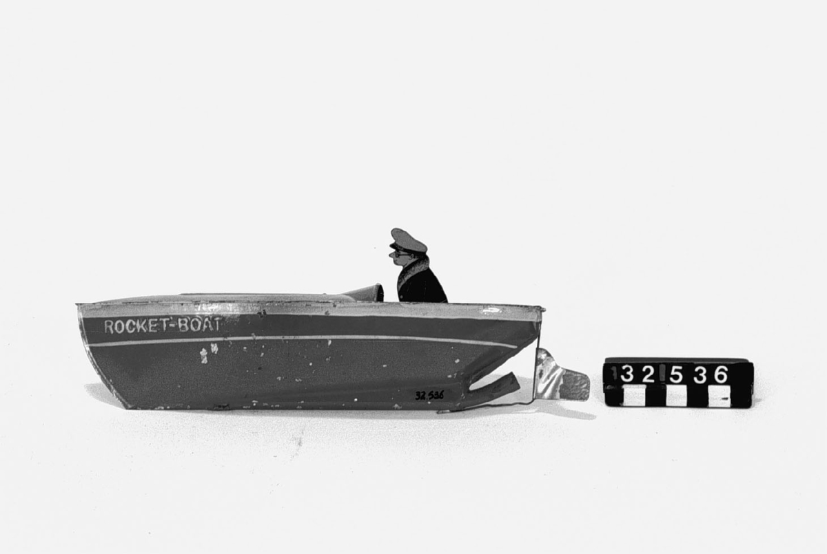 Tillverkad av rödmålad plåt. Leksaksbåten drivs med en Metatablett som vid påtändning värmer luft som via ett rör i aktern driver båten framåt.
