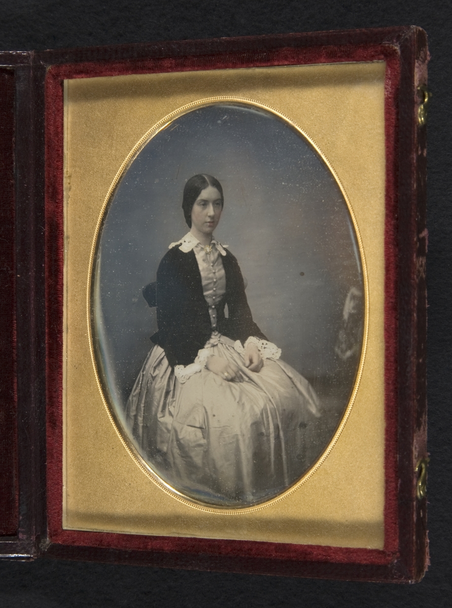 Daguerreotyp. Kolorerat porträtt av ung dam i förgylld ram.