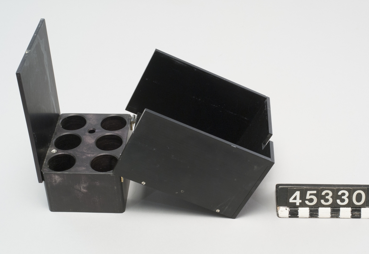 Värmare för preparat i provör. Tillverkare Lab-line Instruments, Inc. modell Multi-blok Heater typ 2091 Till värmaren hör en svart metallbox med plats för sex provrör, det finns en ursparing för termometer i locket.