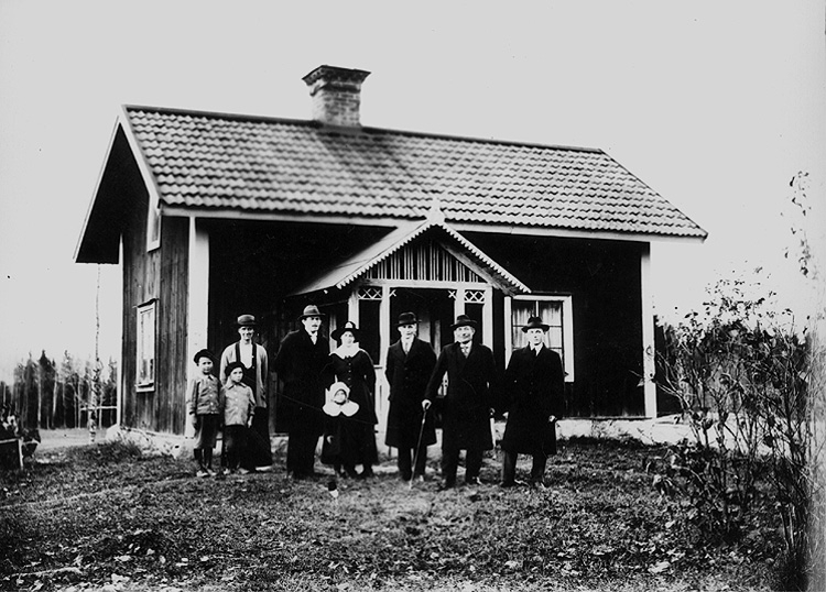 Envånings stuga, grupp 9 personer framför stugan.
Farbror Hultin med gäster vid sin stuga.
Till vänster hushållerskan Anna Åkerby med två pojkar.