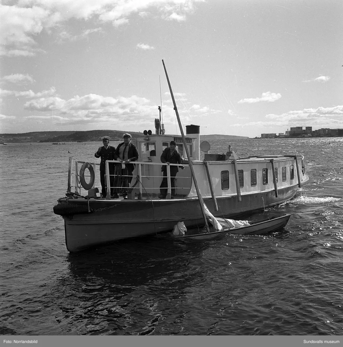 En liten kapsejsad segelbåt bogseras in i hamnen av båten Stuvaren ...