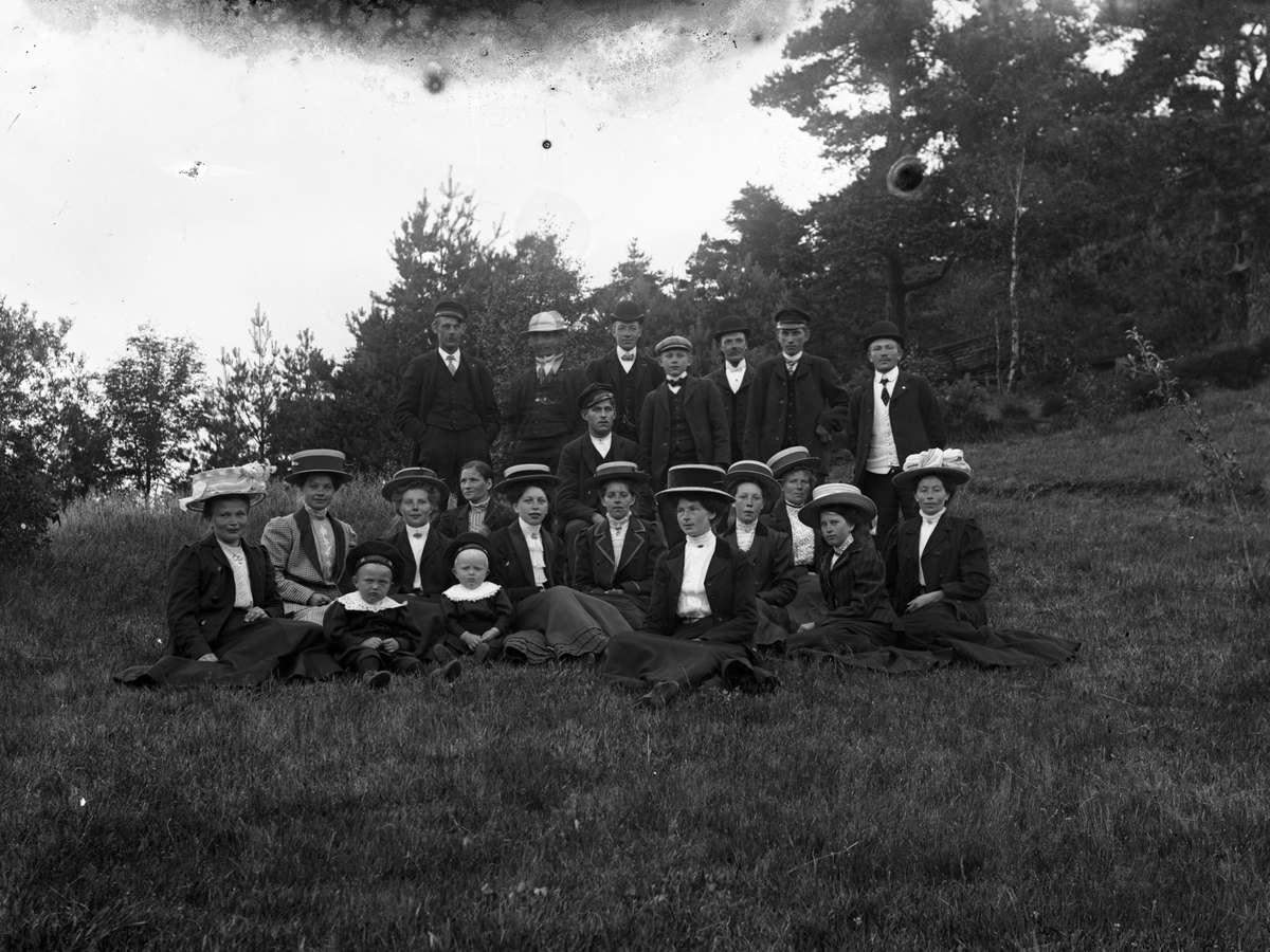Gruppbild med c:a tjugo personer fotograferade utomhus. Mannen med plommonstop, stående trea fr vänster är Klas Johansson i Stenshult, född 1888.
