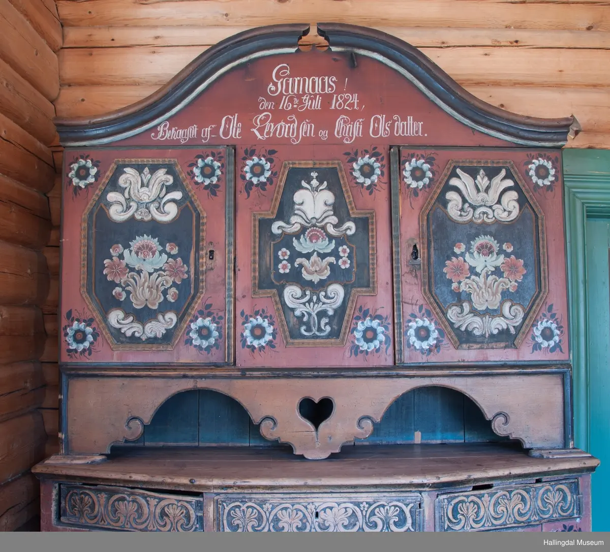 Delene festet med trenagler.  Høy, buet gavl med fremspringende kronlist som øverst har gjennomskåret omvendt hjerte.  Kronlist har hulkil og vulst, og fortsetter på sidene av overskap.  Overskapets front delt i tre felt, med en dør i hvert sidefelt.  Dørene er hengslet til skapets sider.  Hengslene av jern og festet på overkant og underkant av skap og på overkant og underkant av ramme.  Dørene har to profilerte labanker i spor på innsiden.  Låskasetter innfelt i dørblad.  Låsskiltene mangler.  Nøkkel med kløverformede hoder, profilert. En skillevegg midt i overskapet.  To hyller i hvert skap.  Dørene og midtfelt har speil med fyllinger og utskjæringer, akantus i relieff på speilflatene.  Dørspeilene er ovale, åttekantede.  Speil i midtfelt har tilnærmet korsform.  Skjenken har utskåret forplate, i tunger.  Under midfelt får forplaten helt ned til skjenkeplate med gjennombrutt hjerte.  Halvrunde åpninger i hver side. ..........