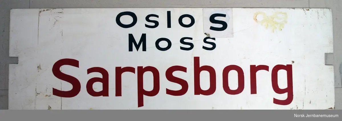 Destinasjons-/vognskilt fra Østfoldbanen.
Påskrift: "Sarpsborg - Moss - Oslo S" og "Oslo S - Moss - Sarpsborg" på hver sin side.