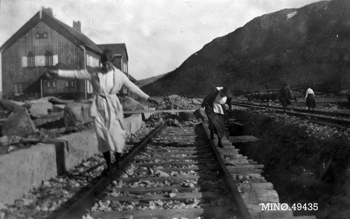 Damer leker på skinnene ved en jernbanestsjon. 