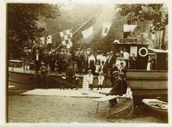 Gruppe med voksne og barn poserer ombord og ved ukjent båt m