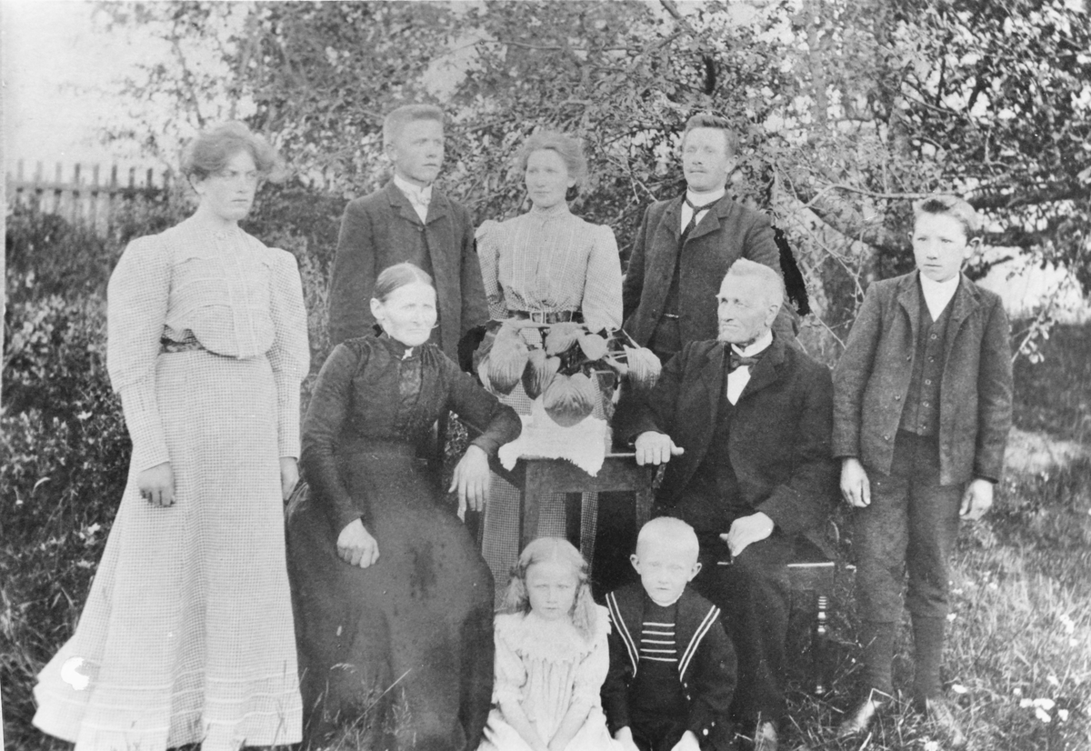Gruppebilde, fra venstre: Olga (ukjent etternavn), Lars, Ragna og Tollef Østby, (ukjent gutt), i midten: Petrine og Syver Østby, foran: Selma og Hans Østby.