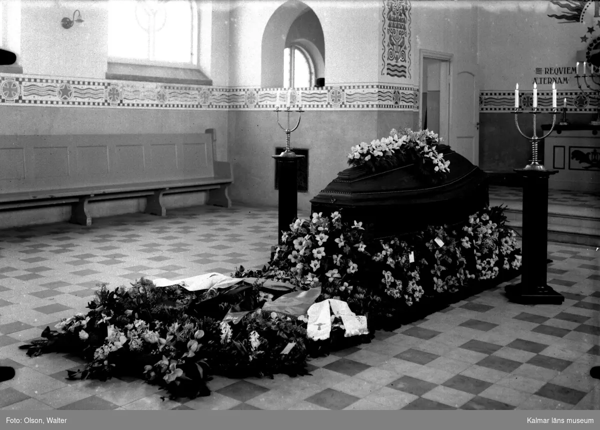 Begravning med kista och blommor vid altaret.