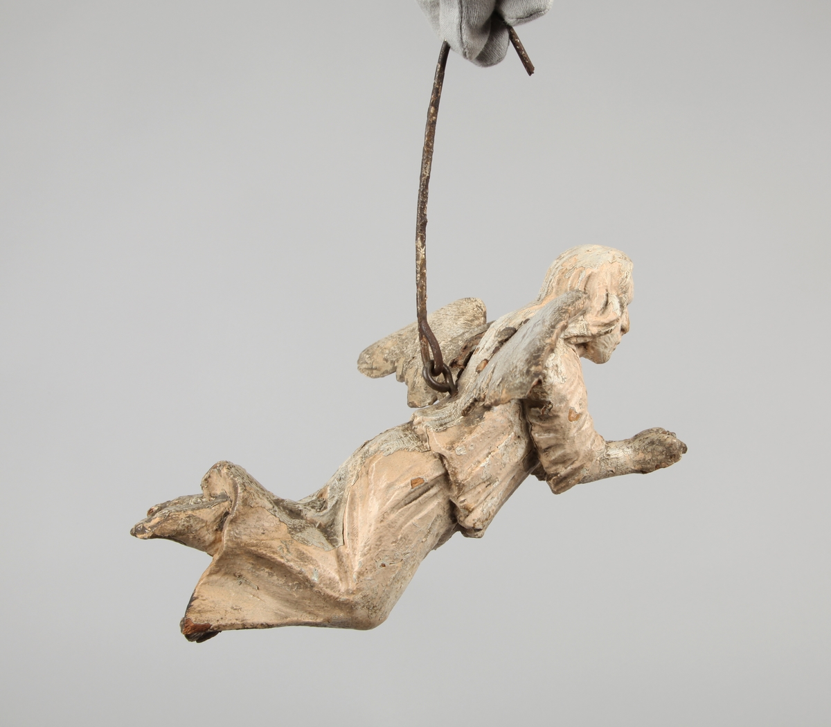 Engleskulptur hengende i en jernbøyle. Vingene er skåret separat og naglet til kroppen.