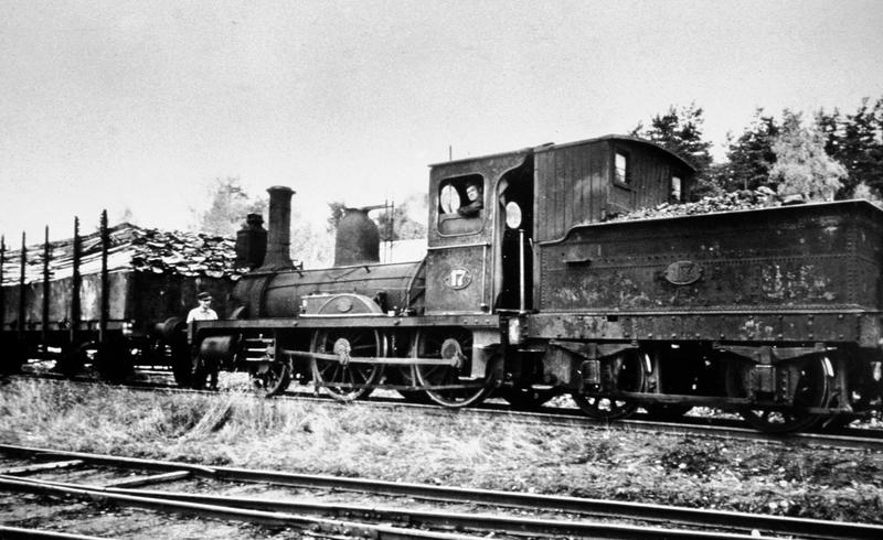Gammelt damplokomotiv som trekker på vogner med plank og tømmer