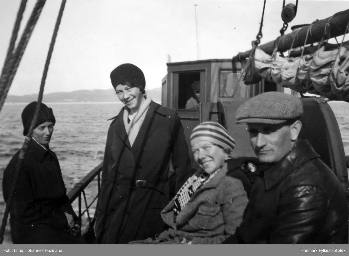 Tre kvinner og en mann fotografert på dekket av en båt