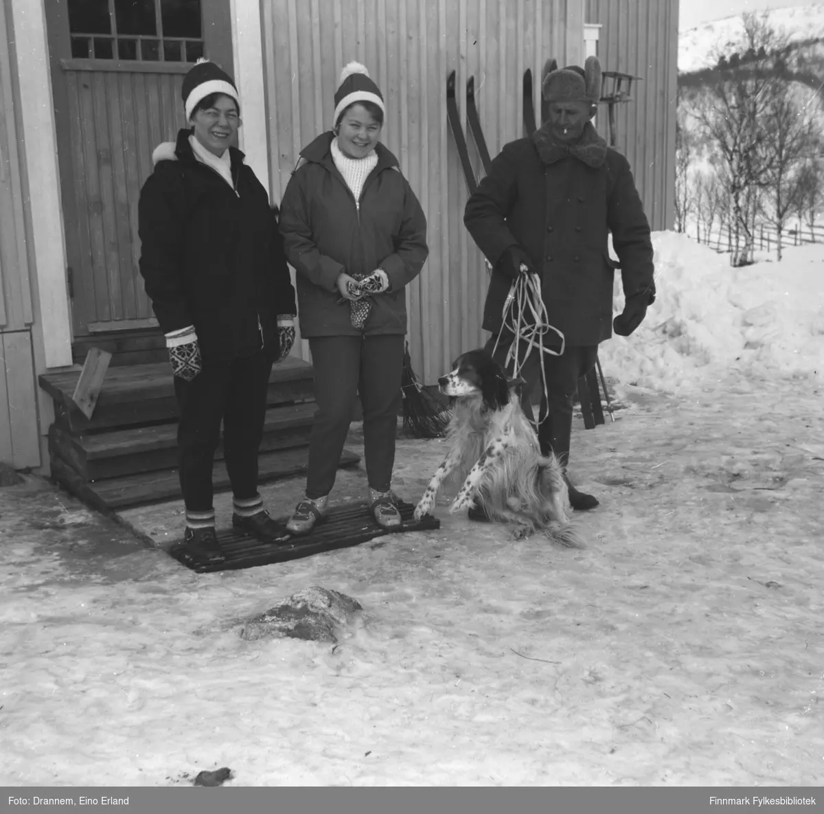 Fra venstre står Jenny Drannem, Turid Karikoski og Uuno Lappalainen med hunden Rexi foran et hus.