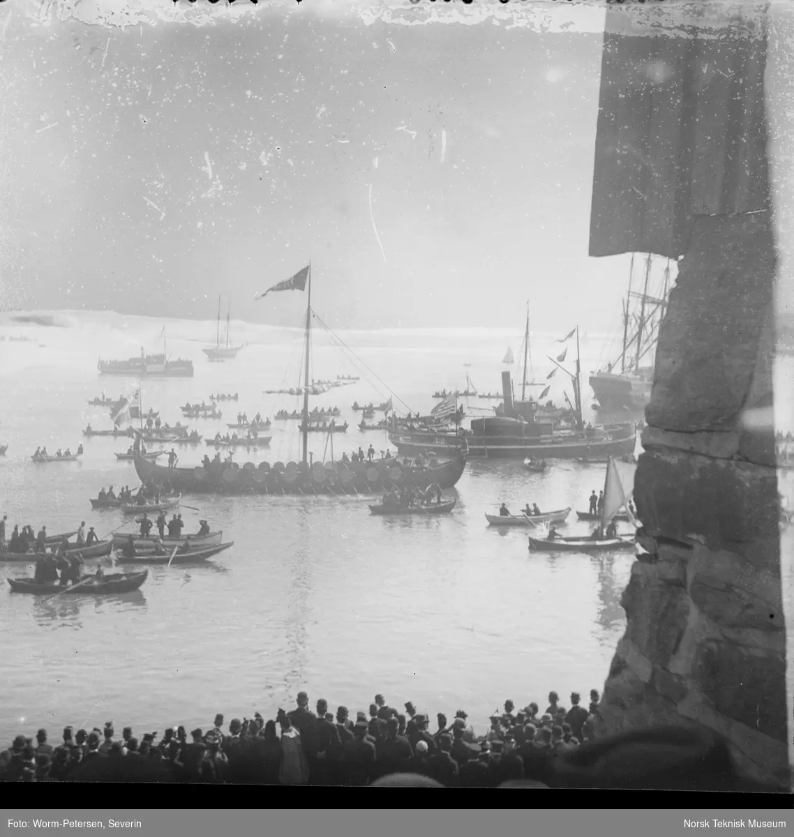 Gokstadskipkopien "Viking" ved avreisen fra Honnørbrygga i Kristiania til verdenutstillingen i Chicago i 1893, sett skrått fra siden og i følge med en stor skute og mange små robåter
