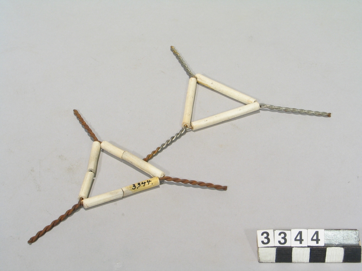 Två st. trianglar av tvinnad järntråd med skyddsrör av oglaserat porslin.