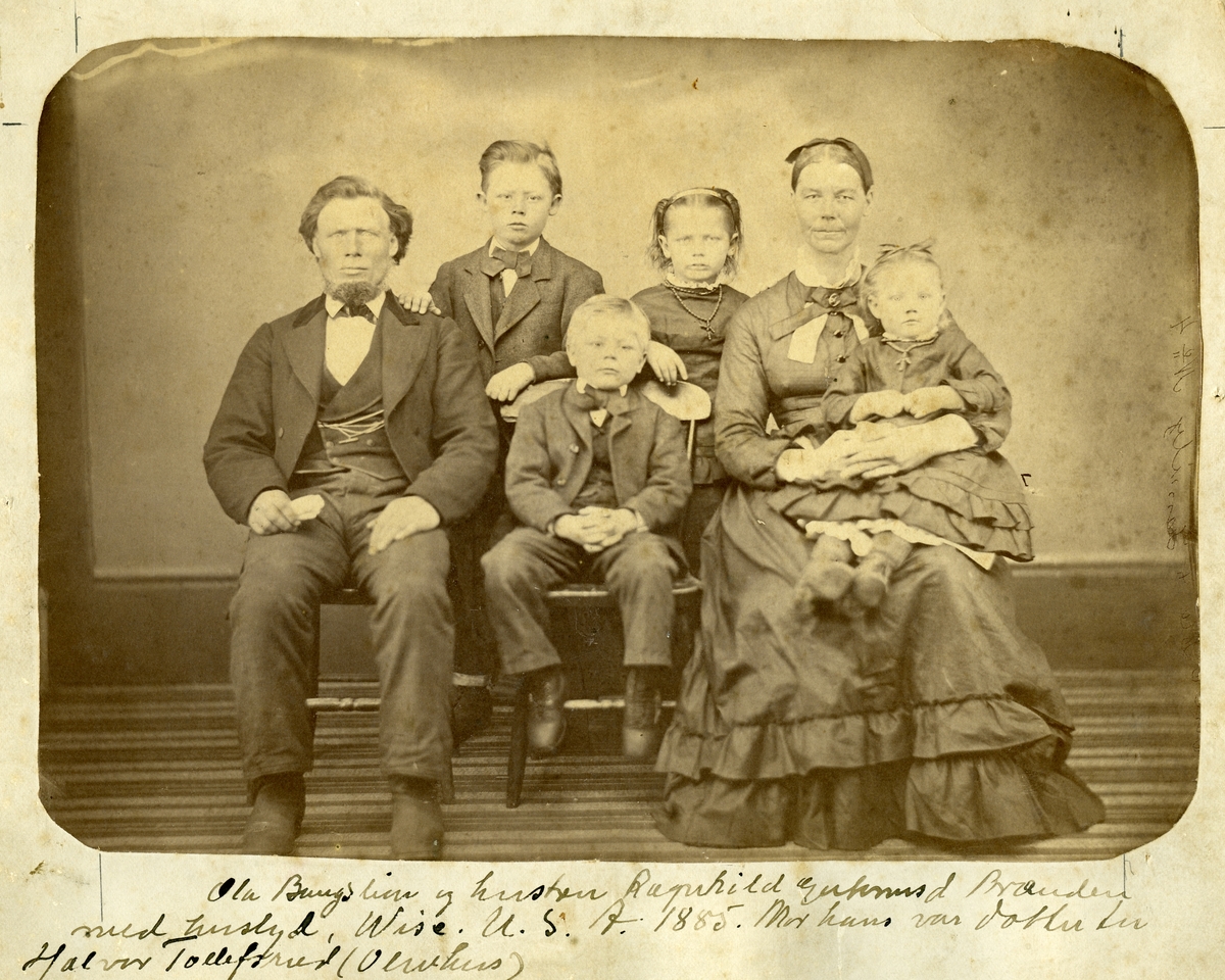 Familieportrett av Ola Bangslien og hustru Ragnhild Brænden og deres fire barn. Bilde er tatt i studio, foran et lerret.