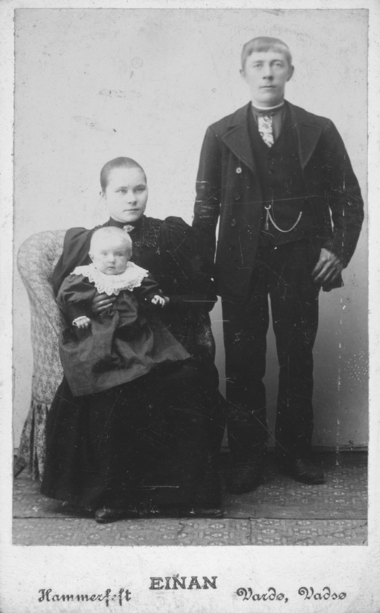 Visittkortportrett av et ungt par. Kvinne sitter med et spedbarn i fanget og mannen står vid siden av dem.