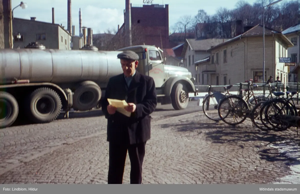 En man fotograferad framför en tankbil vid Forsebron i Mölndal, 1960-tal. I bakgrunden till vänster ses byggnader tillhörande SOAB. I mitten ses Stora Götafors och till höger Götaforsliden 1-5.

För mer information om bilden se under tilläggsinformation.