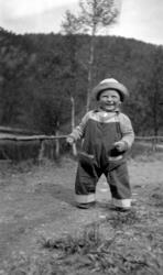 Portrett av en liten gutt langs en landevei, med en elv like