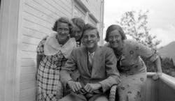 Tre kvinner og en mann på en veranda.Fra venstre ser 
vi, As