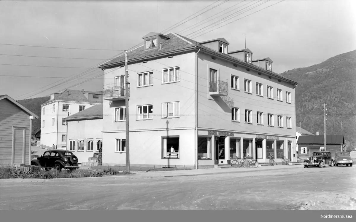 Fra Åndalsnes i Rauma kommune. Vi ser en bygning med Brødrene Nedregård og Åndalsnes Privatbank på gatenivå. Fra Nordmøre museums fotosamlinger. Reg: EFR
