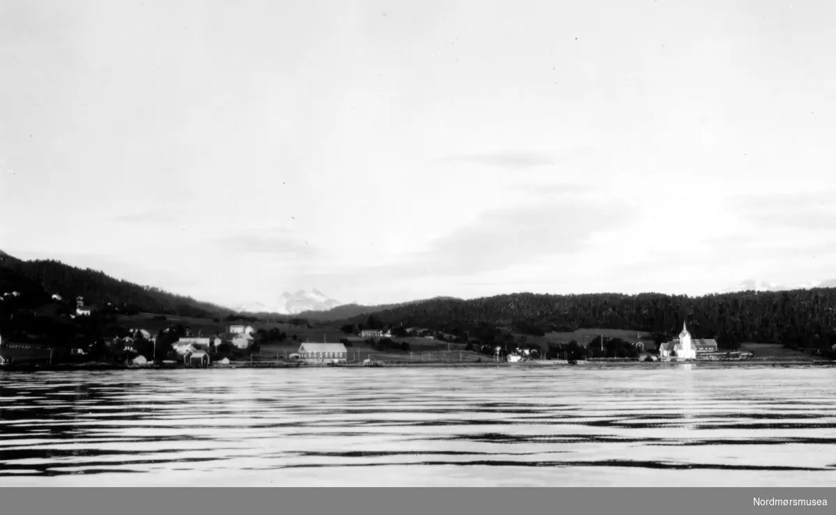 Foto fra Stangvik i Surnadal kommune, sett fra sjøsiden. Her ser vi Stangvik kirke i bakgrunnen, med andre deler av bebyggelsen. Fotograf er Georg Sverdrup og bildet er datert til 1936. Fra Nordmøre Museums fotosamlinger.
