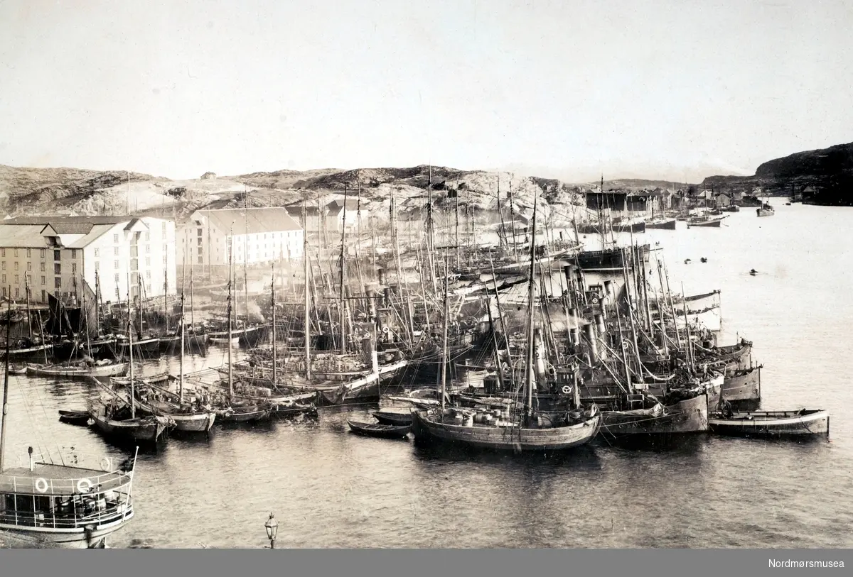 Foto fra Johnsenhuken, hvor vi ser flere fartøyer fylle havneområdet utenfor Huken/Astrupbrygga. Bildet er datert til 25. november 1906, og er stemplet Johan K. Engvig. Fra Nordmøre Museums fotosamlinger. /Reg:EFR2013/
