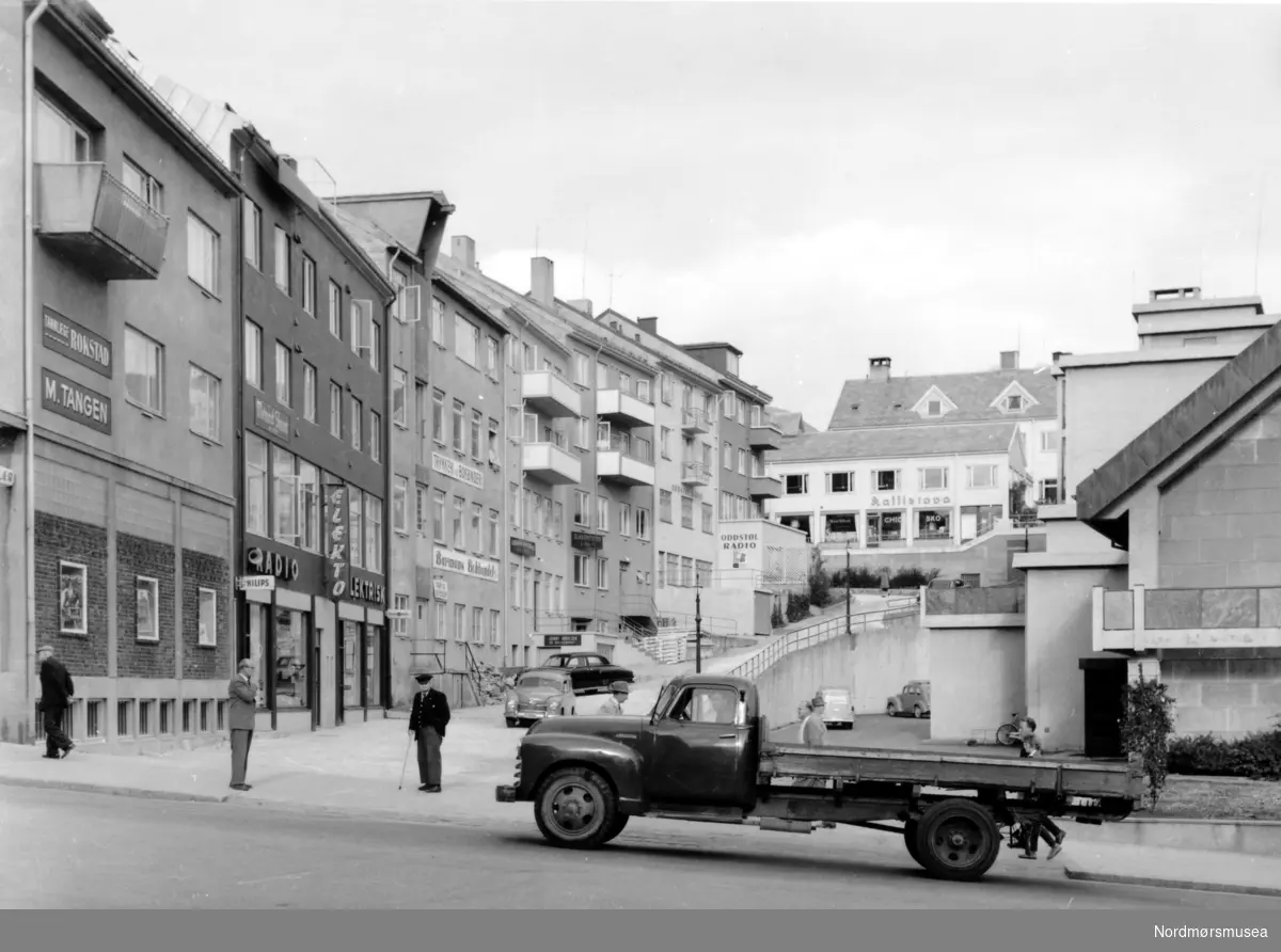 En lastebil på vei opp Kaibakken på Kirkelandet i Kristiansund, med Tangengården ytterst til venstre, Rådhuset, som ble ferdig oppført i 1953 ytterst til høyre og med Grungbakken midt i mellom som leder opp til Kaffistova i bakgrunnen. Bildet er mest sannsynlig fra ca 1953. Fra Nordmøre Museums fotosamlinger.
 -
 Bildet kan ikke være fra 1953. Hauggaten 4, bygg nr. 2 til venstre var opprinnelig erstatningstomt til slakter Alf Tørlen, han hadde fått tegningene godkjent, men prosjektet ble fyllført av Reidar Strømman/Harry Mathisen 1957.12.01, Hauggata 8 lengre oppe ble ikke innflyttet før 1958.02.03., med gullsmed Aasen. (Tilleggsinfo: Andreas Sandvik.)



