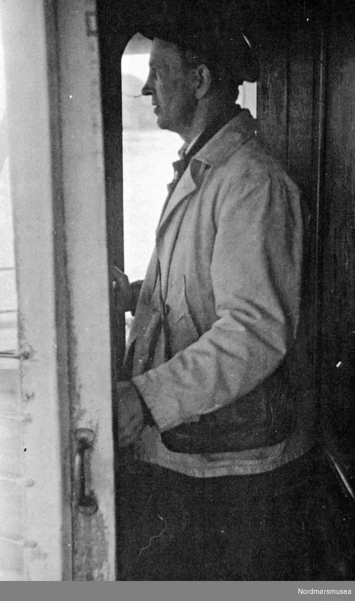foto av føreren
 på en av sundbåtene som trafikkerte havnebassenget i Kristiansund trolig omkring 1910 til 1920 tallet. caps, skyvedør
 Fra Nordmøre museums fotosamlinger.
