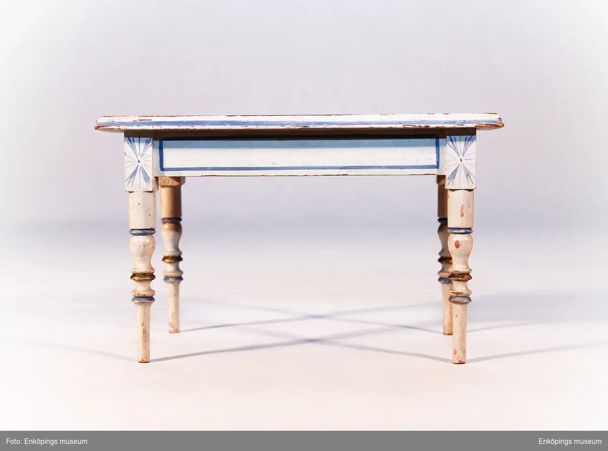 Gråmålat bord med svarvade ben. Dekor av blå färg och guld färg.