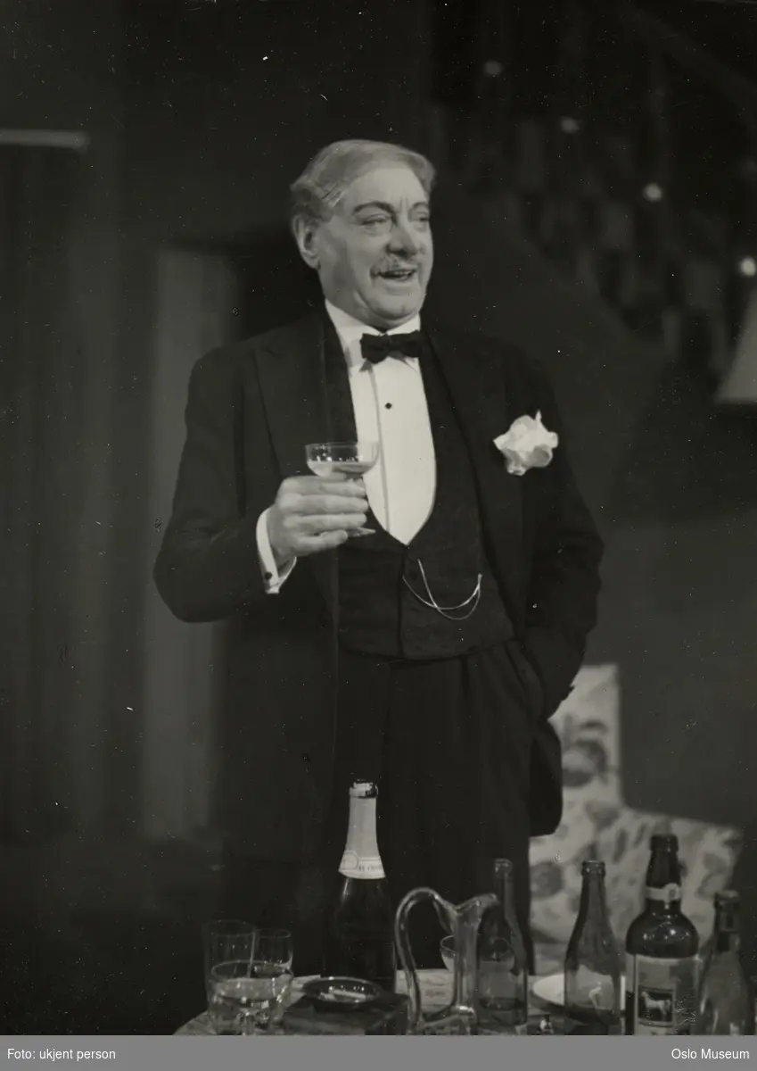 portrett, mann, skuespiller, rollebilde, garasjeeier Victor Andersen i "Andersens" på Nationaltheatret, stående knefigur, kostyme, bord, glass, flasker