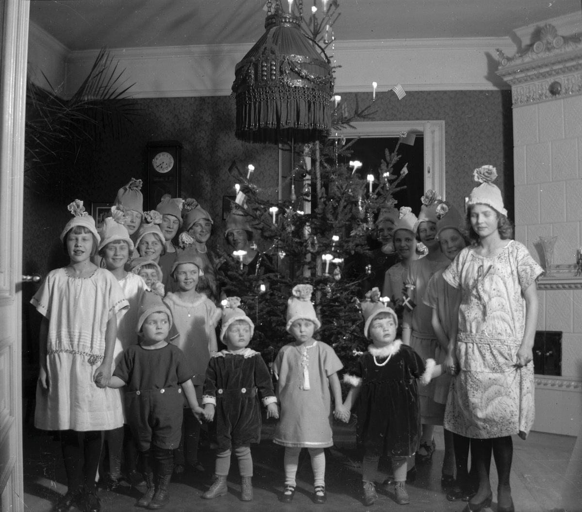 Familjen Brundins kusiner och vänner samlade till julgransplundring. Alla hade små hattar gjorda av kräppapper. Fotot taget i salen på Södra Centralgatan 26.