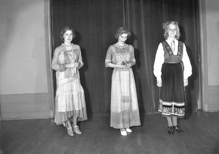 Ett grupporträtt med tre kvinnor i olika klänningar (varav en
i Värendsdräkt).