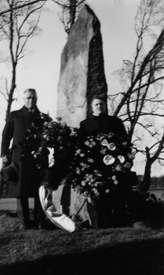 Foto på två män som står framför Per Henrik Lings minnessten med kransar i handen.