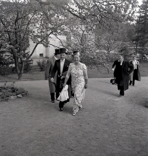 Doktorinnan Tegner, 19/5 1945. Glada bröllopsgäster (med präst) på väg uppför en bred trädgårdsgång. I bakgrunden skymtar ett bostadshus.