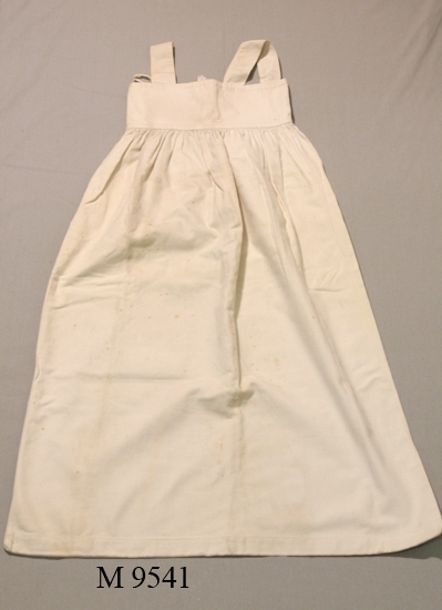 Nattdräkt/sovpåse av vitt kypertvävt 
bomullstyg, med axelband.
Nederdelen är sydd som en påse som är 
rynkad mot ett rektangulärt ok.
Sprund bak (235 mm.) ett runt tränsat hål
på bakstycket (ok).
Mått; L: 980 mm. Br: 255 mm. (överk.), 585 mm. (nedk.).

Inskrivet i huvudbok 1937.