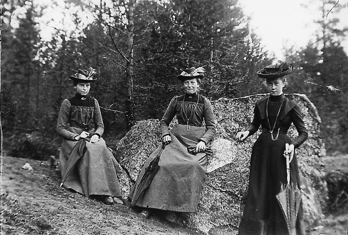 Tre kvinnor vid en stor sten.