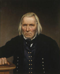 Portrett av Omund B. Birkeland. Mørk drakt med stripet vest, hvit skjorte og svart halsbind. Hviler høgre hånd på et bord.