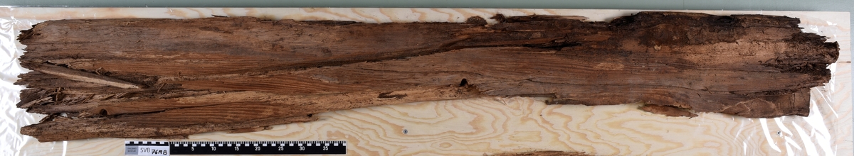 Deler av en rektangulær gravkiste. Det er kistebunnen, kistelokk, kistesidevegger og deler av hodeendegavlen.
Kistelokket er laget av et flatt og rektangulært bord som er laget av ett stykke tre. Bordet er sterkt fragmentert.
Kistesidene er i litt bedre tilstand. Bordene er avlange, rektangulære og laget av et stykke tre hver. Bordene ble festet med spiker til kistebunnen. Det er en spiker igjen i venstre sideveggen. Begge sidebordene har langsgående sprekker og er delvis brudd i flere deler.
Kistebunnen er laget av et flatt og rektangulært bord som er laget av ett stykke tre. Det er flere langsgående sprekker og flere kvisthull. Fargen er mørk brun med enkelte lysere brune partier i hodeenden.  I begge kortender er det rester etter hodegavlen og fotendegavlen og langs venstre siden er det rester etter kisteveggen. Hodeenden er bredere enn fotenden.
Hodeendegavlen er laget av en tykkere rektangulær trekube. Den har brudd opp i flere deler både på grunnen av nedbrytingen og under utgravningen.