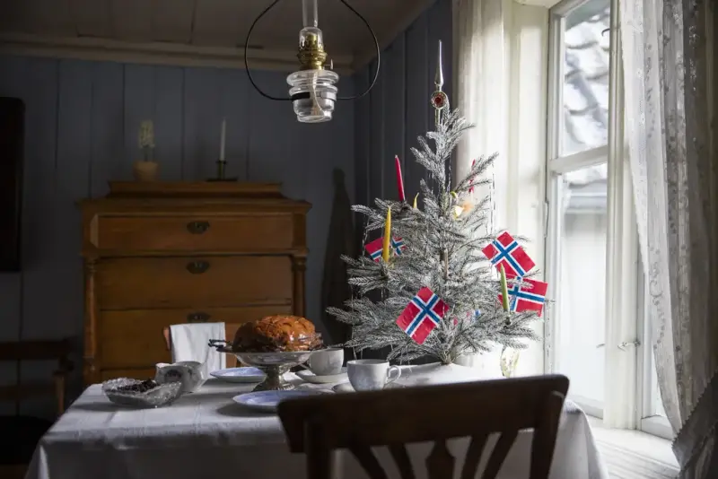 Et dekket bord med julepynt, juletre og norske flagg på på Norsk Folkemuseum