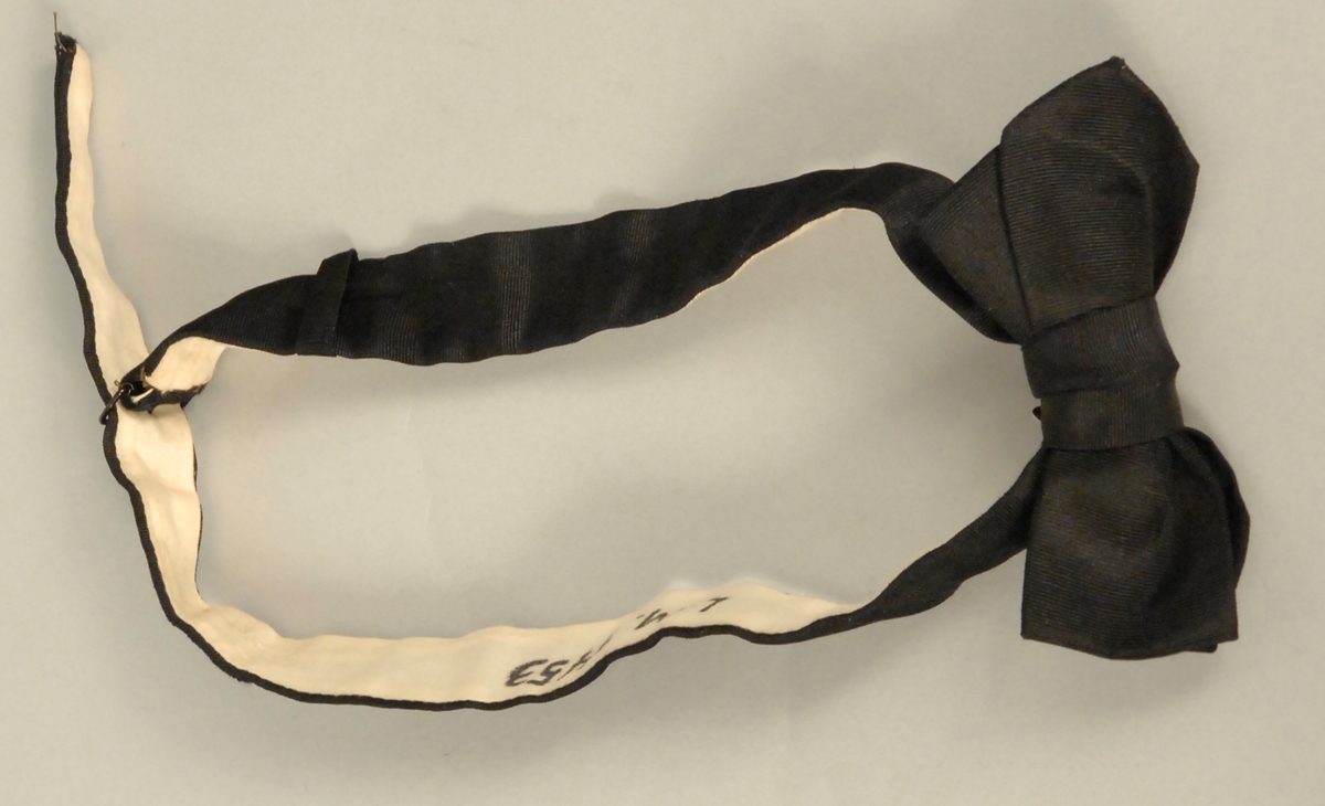 A: Jakke, Svart klede, krage med silkeslag. Enkeltspent, 1 trekt knapp, 3 trekte knapper på kvar arm. Svart silkefor. L.71,5 cm bredde ved skuldrane 45 cm
B: Bukse, svart klede, silkeripsbånd i sidene. L. 103 cm, Vidde nede 24 cm
C: Vest, svart klede, svart silkefor i rygg, foret med lystripet sateng. Enkeltspent med 4 trekte knapper, 4 lommer. L.48,5 cm x 38 cm
D: Sløyfe, Sort silkerips 55cm x 3,5 cm