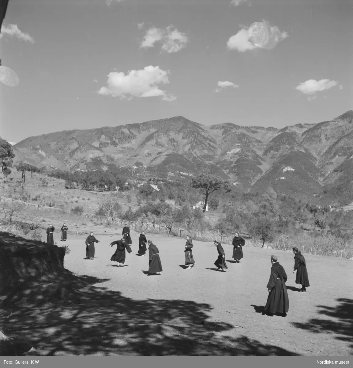 Munkar som spelar fotboll med Levantos berg i bakgrunden.
